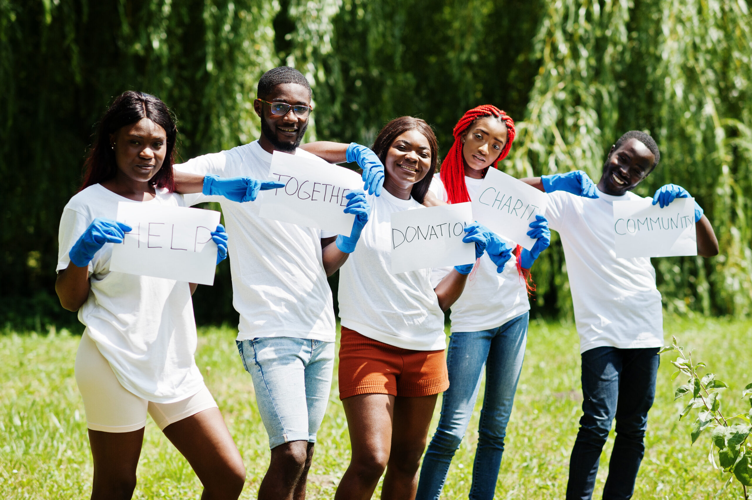 Home group of happy african volunteers hold blank board in park. afri